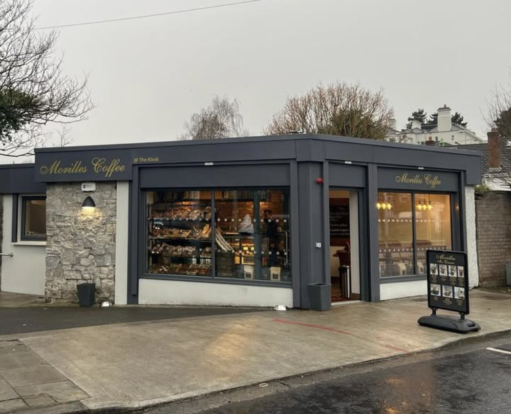 Modern coffee shop exterior with large windows showcasing pastries and a welcoming entrance.